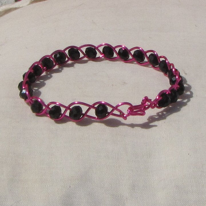 Hot shiny pink coloured copper plaited bracelet with black beads